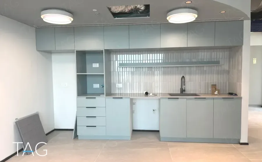 מטבח משרדי בACRO BUSINESS CAMPUS עם ארונות אפורים בהירים וחיפוי מחורץ - תג נכסים