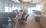 שורות עמדות עבודה מול חלונות וקיר עץ ממוחזר במגדל רוטשילד 22