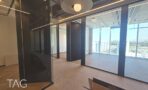 חלל משרדי בACRO BUSINESS CAMPUS עם מחיצות זכוכית, תאורה מעוצבת ונוף עירוני - תג נכסים