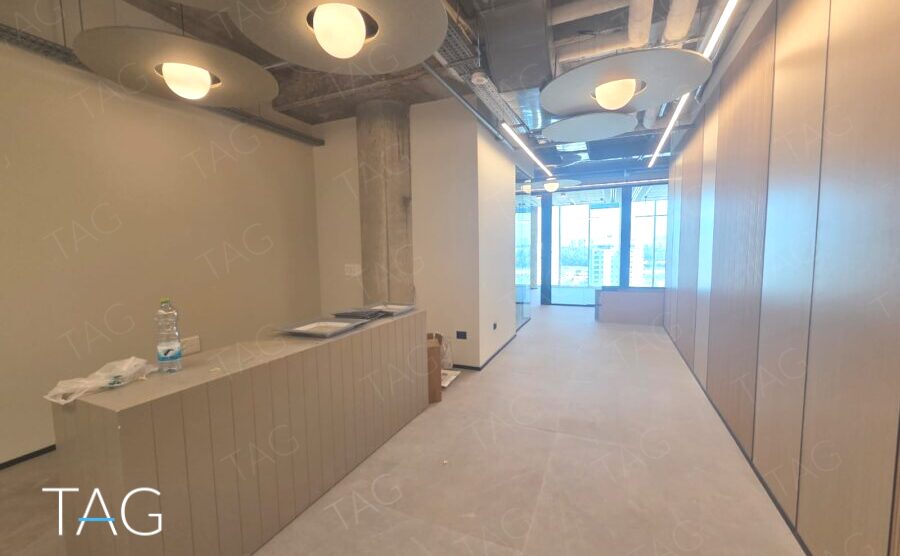 אזור משרדי בACRO BUSINESS CAMPUS עם חיפוי קיר עץ ותאורה תלויה - תג נכסים