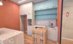מטבח עם ארונות לבנים וירוקים וקיר טרקוטה במשרד 180 מ״ר במגדל אקרו