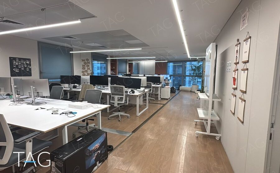 אופן ספייס עם שורות שולחנות עבודה לבנים ופרקט עץ במשרד להשכרה במגדל פלטינום בתל אביב
