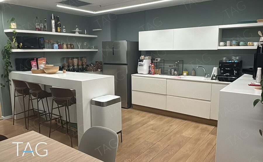 מטבחון לבן עם דלפק בר וקיר ירוק אפרפר במשרד במגדל פלטינום
