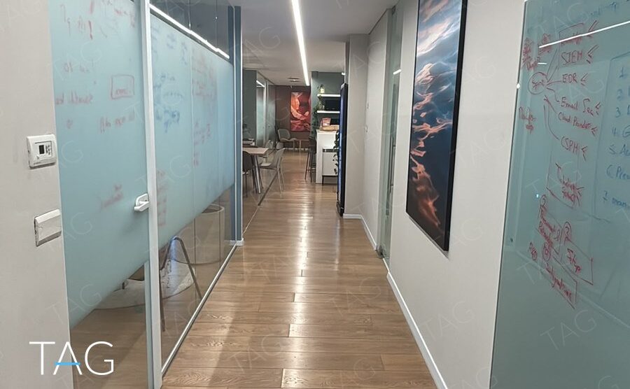 מסדרון עם קירות זכוכית חלבית ופרקט עץ בין חדרי העבודה במשרד בתל אביב