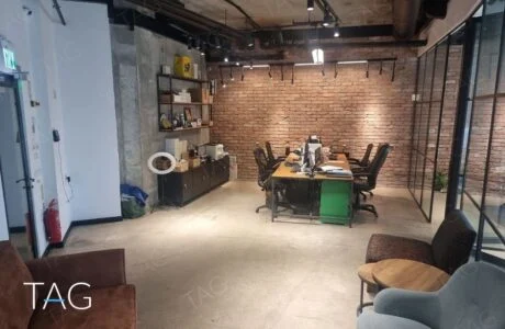 אופן ספייס עם קיר לבנים אדומות, עמדות עבודה ופינת ישיבה במשרד להשכרה במגדל ספיר ברמת גן