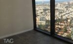 חדר ריק עם חלון מהרצפה עד התקרה ונוף לים ולבניינים מקומה גבוהה