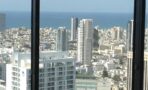 נוף אל הים ואל בנייני המגורים והמשרדים בתל אביב מבעד למסגרת חלון שחורה