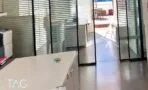 מחיצות זכוכית עם פסי הצללה ודלת הזזה שדרכה נראה הגג של המשרד להשכרה