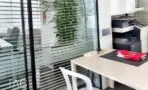 עמדת עבודה עם שולחן בהיר, כיסא לבן ומדפסת ליד מחיצת זכוכית במשרד בתל אביב