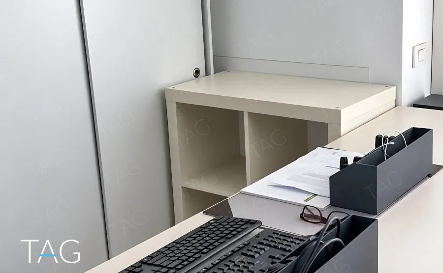 ארון הזזה אפור, כוננית בגוון בז' ושולחן עם מקלדות במשרד להשכרה בתל אביב