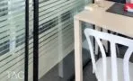 מחיצת זכוכית עם פסים אופקיים, שולחן בגוון עץ בהיר וכיסא לבן במשרד להשכרה
