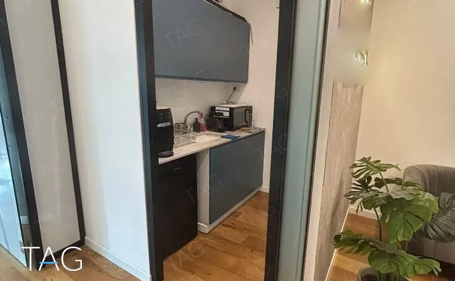 מטבחון עם ארונות בגוון כחול כהה, משטח עבודה בהיר וכיור ליד הכניסה למשרד במגדל ספיר