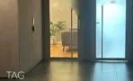 דלתות כניסה מזכוכית ממסגרת אפורה במסדרון הקומה, ומאחוריהן קבלה עם ספה ופרקט במגדל ספיר
