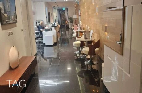 מסדרון קבלה במשרד להשכרה במגדלי הארבעה עם רצפת גרניט שחור וקיר חיפוי עץ מואר