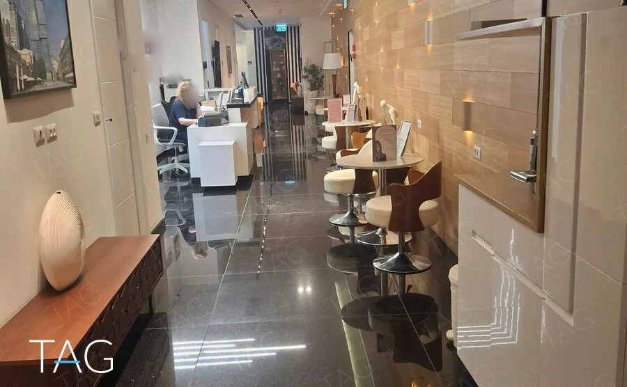 מסדרון קבלה במשרד להשכרה במגדלי הארבעה עם רצפת גרניט שחור וקיר חיפוי עץ מואר
