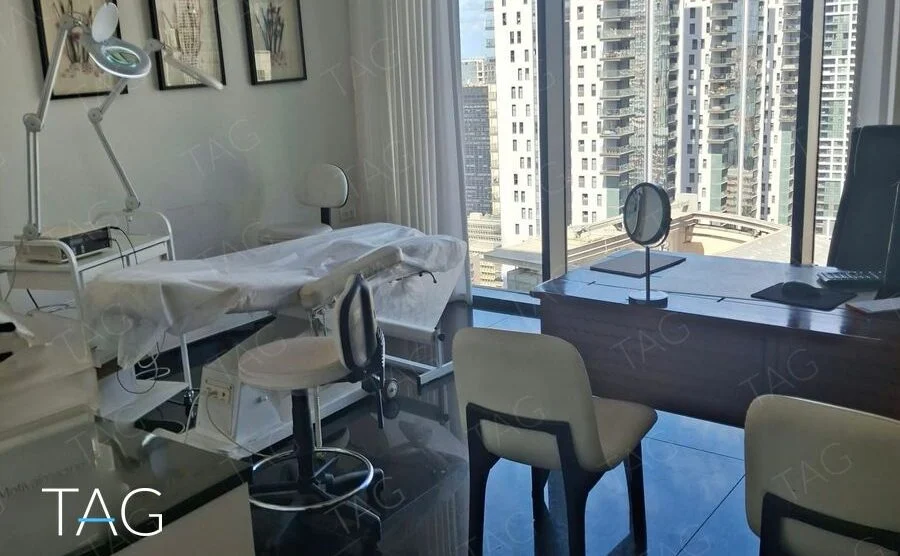 חדר מרוהט עם שולחן עבודה וחלון רחב הפונה למגדלי מגורים בתל אביב