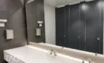 שירותים מעוצבים בקומה עם כיור לבן ארוך וחיפוי אריחים אפורים כהים במגדל סקיי טאוור