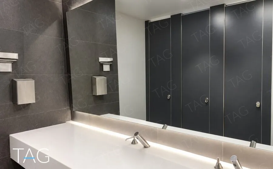 שירותים מעוצבים בקומה עם כיור לבן ארוך וחיפוי אריחים אפורים כהים במגדל סקיי טאוור