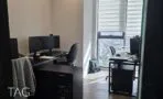 חדר עבודה עם שולחנות כהים, מסכים וחלון גבוה עם וילון זברה הצופה לעיר, משרד במגדלי אלון