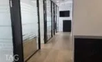 מסדרון עם פרקט עץ טבעי לאורך חדרים במחיצות זכוכית חלבית בפרופיל שחור, משרד במגדלי אלון