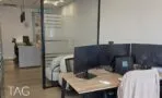חדר עבודה זוגי עם שולחן עץ ומסכים, מבט דרך מחיצת זכוכית אל עמדת הקבלה, משרד להשכרה במגדלי אלון
