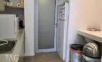 פינת המטבחון עם מקרר, משטח בהיר ופרקט עץ ליד דלת היציאה, משרד במגדלי אלון תל אביב