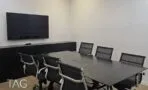 חדר ישיבות עם שולחן כהה, כיסאות רשת שחורים, מסך על הקיר ותאורה ליניארית תלויה, משרד במגדלי אלון