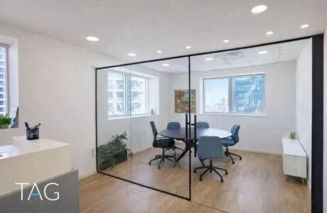 חדר ישיבות בקירות זכוכית עם שולחן עגול וכיסאות כחולים במשרד להשכרה במגדל משה אביב רמת גן