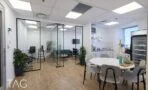 מטבחון ופינת ישיבה עם שולחן עגול לבן ליד חדרי זכוכית במשרד להשכרה במגדל משה אביב