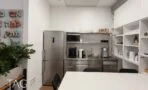 מטבחון נירוסטה עם מקרר ושולחן אוכל לבן במשרד בבית ו.א