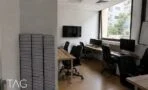 חדר עבודה עם שולחנות עץ בהיר ומסך על הקיר במשרד להשכרה ברוטשילד