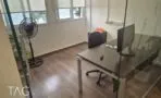 חדר עבודה סגור במחיצות זכוכית עם שולחן כהה וחלונות לעצים ברחוב
