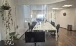 מבט מחדר הזכוכית אל האופן ספייס, עם פרקט עץ כהה ותאורה שקועה בתקרה