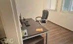 חדר מנהל עם שולחן עץ כהה, כיסא מנהלים מעור וחלון עם וילון בהיר
