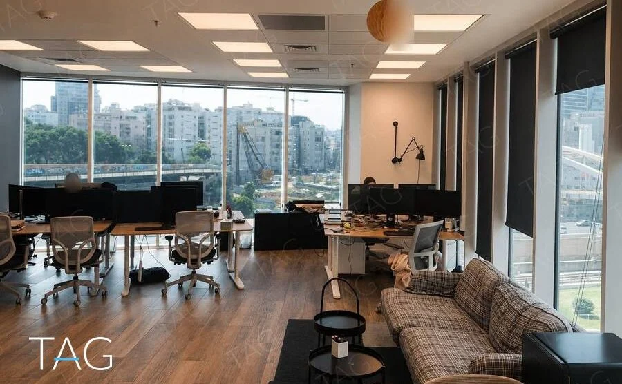 אופן ספייס עם עמדות עבודה, פרקט עץ וחלונות גבוהים במשרד להשכרה במגדל WE בתל אביב