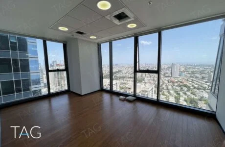 חדר פינתי עם חלונות מרצפה עד תקרה ונוף רחב לעיר ולגגות בתל אביב, פרקט כהה וספוטים עגולים