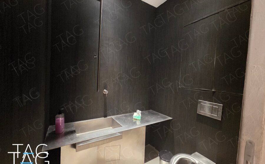 חדר שירותים בחיפוי קירות כהה עם כיור ומשטח נירוסטה במשרד בנמל תל אביב