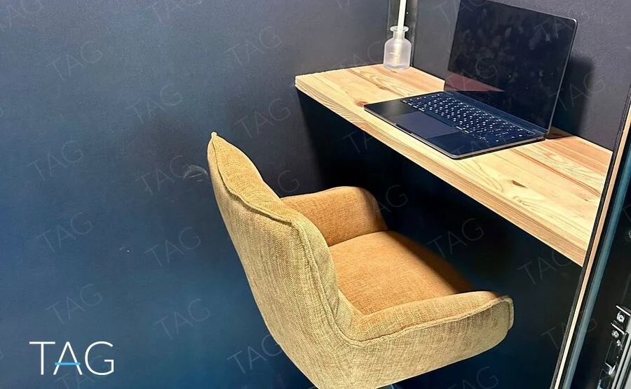 תא שיחה סגור עם כיסא בר מרופד, משטח עבודה מעץ וקירות כהים