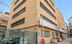 חזית בניין משרדים בגוון חול עם פסי חלונות אופקיים בסמטה להולכי רגל באזור רוטשילד בתל אביב