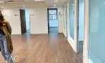 שורת חדרים בחזית זכוכית לצד מרחב פתוח עם פרקט חם במשרד בתל אביב