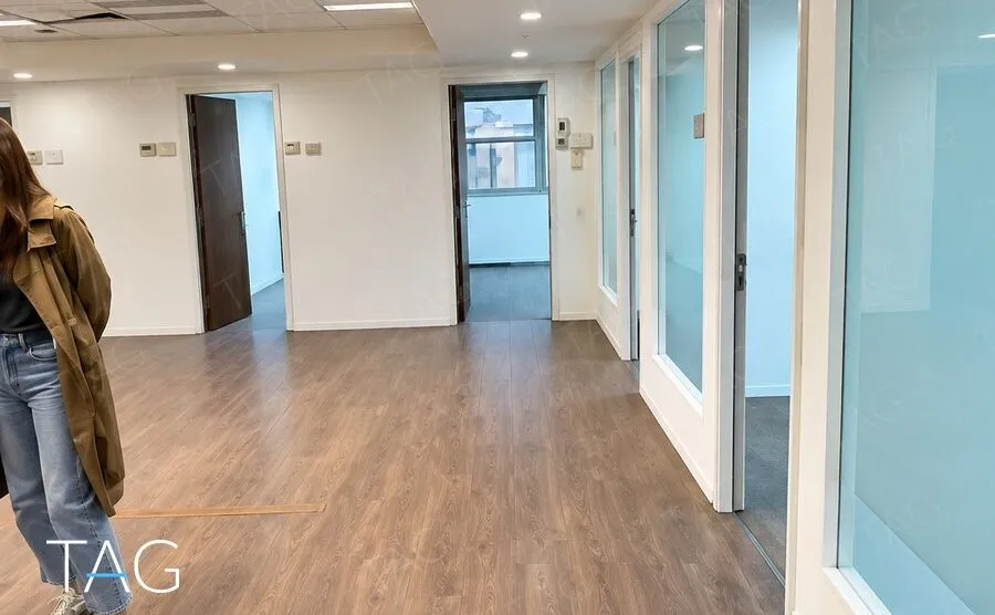 שורת חדרים בחזית זכוכית לצד מרחב פתוח עם פרקט חם במשרד בתל אביב