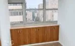 חדר משרד פרטי עם ארונות עץ בנויים לאורך חלון רחב ונוף לבנייני העיר
