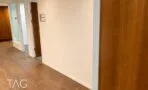 מעבר בין חדרים עם דלתות עץ, קירות לבנים ותאורה שקועה בתקרה