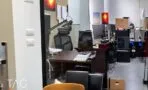 חדר מנהל עם שולחן כהה וכיסא ארגונומי, מבט לאזור עבודה עם מחשבים
