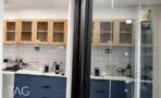 מטבחון עם ארונות עליונים מעץ, ארונות תחתונים בכחול כהה וחיפוי אריחים לבנים