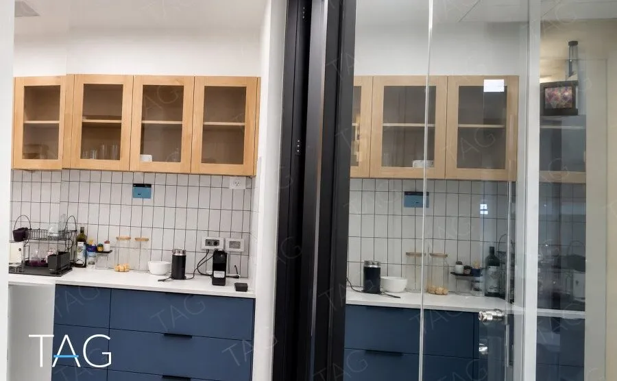 מטבחון עם ארונות עליונים מעץ, ארונות תחתונים בכחול כהה וחיפוי אריחים לבנים