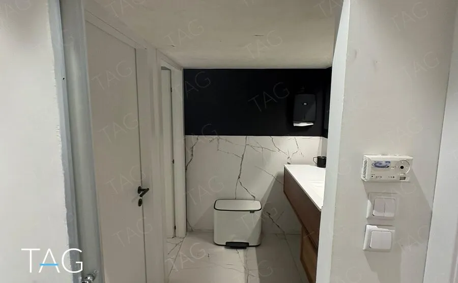 חדר שירותים מחופה אריחים בדוגמת שיש עם ארון כיור מעץ, משרד להשכרה ליד הבימה