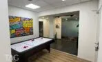 מבואה עם שולחן הוקי אוויר ומעבר לאזור עם ריצוף אבן, משרד להשכרה ליד כיכר הבימה בתל אביב