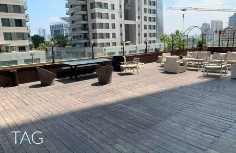 מרפסת דק עץ רחבה עם מערכות ישיבה בהירות ומעקה זכוכית במשרד להשכרה במגדל פלטינום בתל אביב