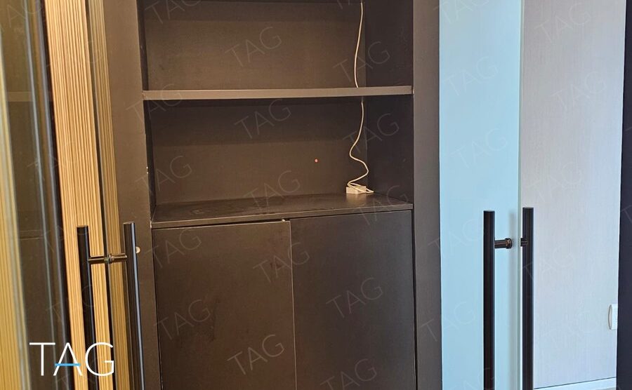 ארון נגרות שחור עם מדפים פתוחים ודלתות זכוכית חלבית עם ידיות שחורות במשרד במגדל ספיר